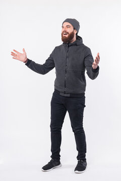 Full length photo of young bearded man making welcome gesture.