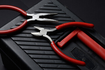 The flat nose pliers and pasatige are on the tool box. close-up.