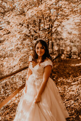  bride in white wedding dress walks through autumn forest on fallen orange leaves