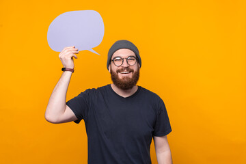 Photo of happy bearded hipster man holding speech bubble over head.
