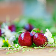 Two bright ripe cherry berries and meadow flowers closeup, selective focus, harvest, healthy diet, summer background