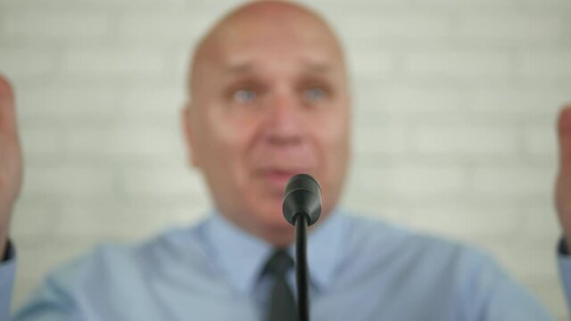 Blurred Image of a Businessman Speaker in a Press Conference Talking at the Microphone and Gesturing