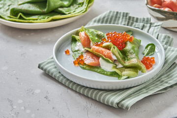 Green spinach crepes with smoked salmon, red caviar and yogurt sauce