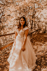Obraz na płótnie Canvas bride in white wedding dress walks through autumn forest on fallen orange leaves