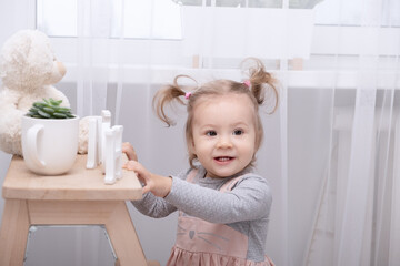 funny toddler girl playing with toys at home in white room
