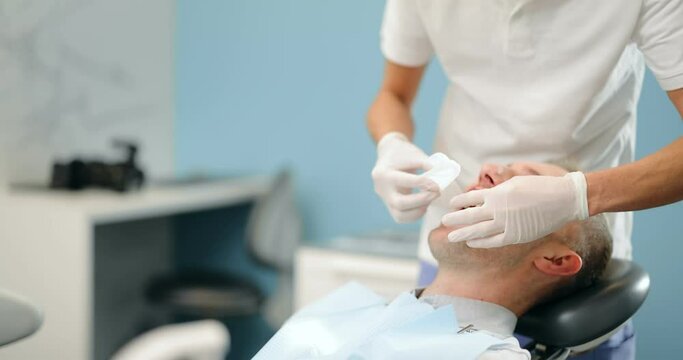 Young dentist wearing optragate for the male patient, preparing for the dental checkup. Regular visit to the orthodontist
