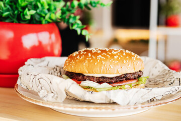 burger on a plate on a wooden table next to a red pots