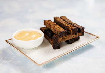 croutons with cheese sauce on a rectangular plate on a blue background