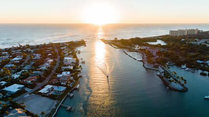 An epic sunrise aerial shot over the Jupiter Inlet with a yacht coming in from the sea.