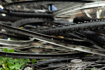 old wheels, rims, and bicycle tires on the street in a pile
