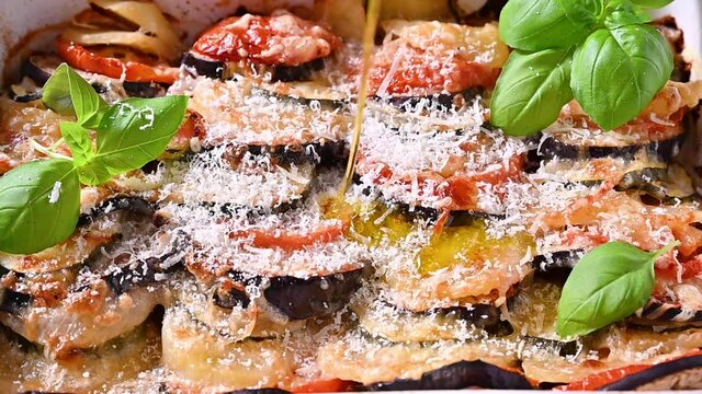 olive oil is poured into lasagna. Traditional italian food. Baked eggplant, tomatoes with sauce, parmesan and basil. Rustic food for a healthy diet. Vegetables for lunch.	