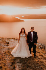 Fototapeta na wymiar wedding newlyweds in a white dress and suit walk in the summer on the mountain above the river.