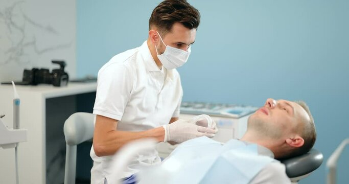 Young dentist wearing optragate for the male patient, preparing for the dental checkup. Regular visit to the orthodontist