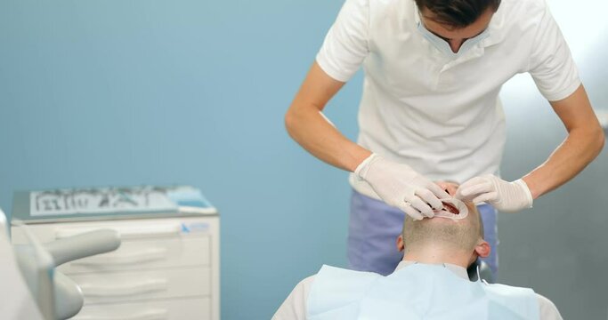 Young dentist wearing optragate for the male patient, preparing for the dental checkup. Regular visit to the orthodontist
