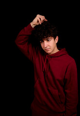 Attractive young man with curly hair posing on black studio background