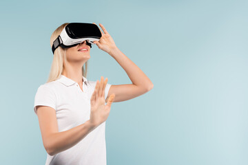 happy woman in vr headset gesturing isolated on blue