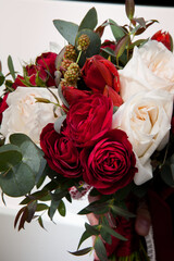 a beautiful and expensive bouquet with red and white roses and eucalyptus greens and raspberries