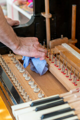 Setting up an old piano. The master repairs an old piano. Deep cleaning the piano. Hands of professional worker repairing and tuning an old piano. toned