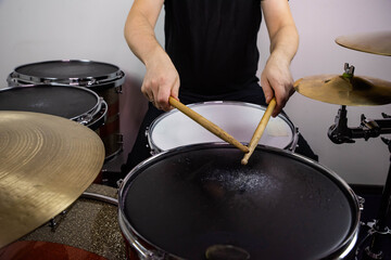 Professional drum set closeup. Man drummer with drumsticks playing drums and cymbals, on the live music rock concert or in recording studio   