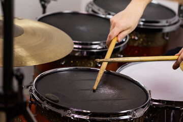 Professional drum set closeup. Man drummer with drumsticks playing drums and cymbals, on the live music rock concert or in recording studio   