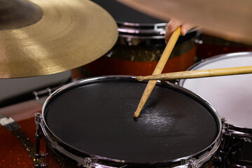 Professional drum set closeup. Man drummer with drumsticks playing drums and cymbals, on the live music rock concert or in recording studio   