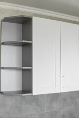 Obraz na płótnie Canvas Custom kitchen cabinets installation with a white furniture facades mdf. Gray modular kitchen from chipboard material on a various stages of installation. A frame furniture fronts mdf profile.
