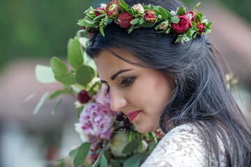 Closeup portrait of beautiful young girl in traditional Slavic dress with wreath of summer flowers. Ethno folk style cheerful female on abstract background in summer at floral feast. Expressive face.