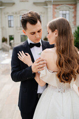 beautiful, gentle and happy bride and groom hugging on background of building