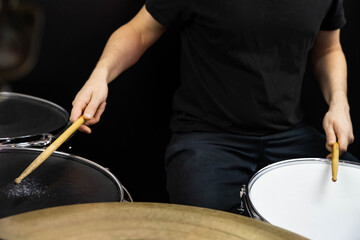 Professional drum set closeup. Man drummer with drumsticks playing drums and cymbals, on the live music rock concert or in recording studio   