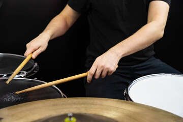 Professional drum set closeup. Man drummer with drumsticks playing drums and cymbals, on the live music rock concert or in recording studio   