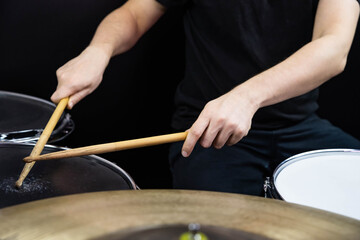 Professional drum set closeup. Man drummer with drumsticks playing drums and cymbals, on the live music rock concert or in recording studio   