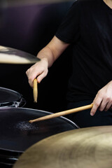 Professional drum set closeup. Man drummer with drumsticks playing drums and cymbals, on the live music rock concert or in recording studio   