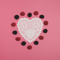 Valentine's Day creative pink flat lay arrangement made of red and purple candy and embroidery paper heart. Minimal concept.