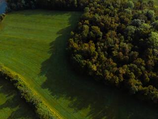 birds eye view of the green hills, forest and mountain river. Nature landscape. Agriculture fields. Summer day. Misace, Mosnje, Slovenia