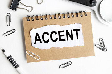 accent, text on white paper over white background. notebook, pen.