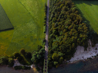 Aerial view of the railway connection. Summer, sunny weather. Metal bridge over a mountain river. Transport and freight transportation concept. Tourism. Fields and houses. Misace, Slovenia.