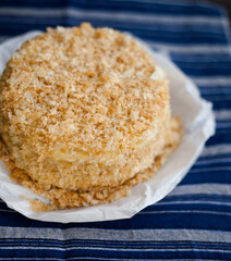 homemade napoleon cake decorated with crumbs and blueberries on a dark background
