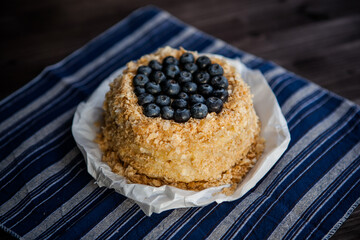 homemade cake decorated with crumbs and blueberries on a dark background