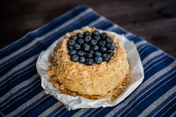 homemade cake decorated with crumbs and blueberries on a dark background