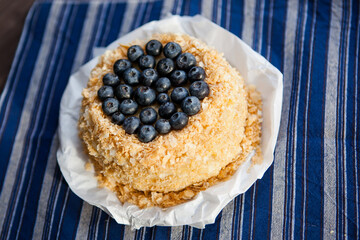 homemade cake decorated with crumbs and blueberries on a dark background