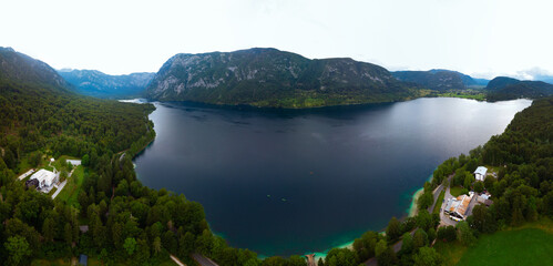 Fototapeta na wymiar Aerial wide view of the Bohinj lake. Travel and tours concept. Beautiful landscape ot the Triglav mountains, national park, summer forest and the church, Slovenia, Europe