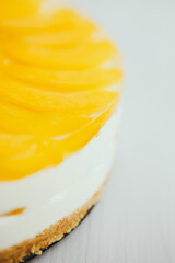 classic homemade cheesecake with a fruity yellow filling on top on a light background
