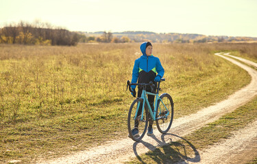 A young guy on a sports bike stopped on a country road, looking in the direction of traffic. Exercise in the open air.