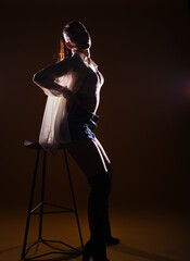 Obraz na płótnie Canvas Full-length silhouette portrait on a dark background of a sensational woman posing with a high chair