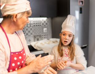 Grandmother and granddaughter preparing doughnuts at home