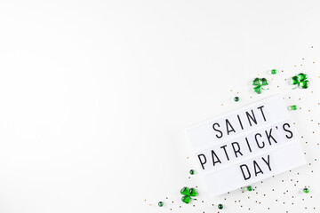 Lightbox with Saint Patricks day text, shamrock symbols made of green hearts and stars confetti on white background. Flat lay Irish holiday party card Spring 17 march lucky clover design. Copy space