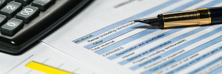 Calculator and pen with accounting report and financial statement on desk. Accounting business plan concept. Selective focus