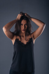 Fototapeta premium Portrait of a beautiful female model looking serious at the camera while touching her brunette hair