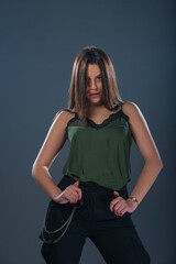 Portrait of a sexy young female model  standing in a studio and wearing dark green top and black pants