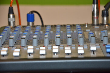 Professional audio mixing console with faders and adjusting knobs,